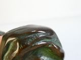 un gros plan sur une main tenant une statuette de grenouille