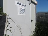 une cabane de toilettes blanche avec une pancarte sur le côté