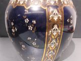 un vase bleu orné de motifs dorés, posé sur une table