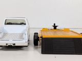 a white truck and a yellow truck on a white floor