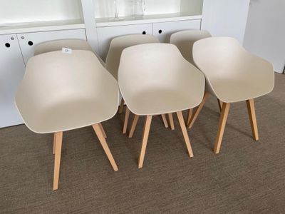 four white chairs with wooden legs in front of a white bookcase