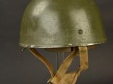 an army helmet on a metal stand against a black background