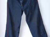 denim pants hanging on a hanger on a white wall