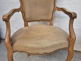 an old chair with a tan upholstered seat is sitting on a concrete floor