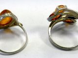 pair of silver rings with orange stones on them on a white surface