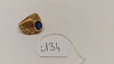 une bague en or sertie d'une pierre bleue est posée sur une étiquette