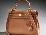 a brown leather handbag with gold hardware on a grey background