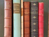 several old books are lined up on a shelf in a library