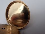 a gold pocket watch sitting on a white surface