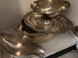 silver dishes and spoons sitting on a shelf in a kitchen