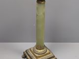 un vase vert posé sur un socle à la base dorée