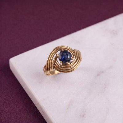 une image d'une bague en or avec une pierre bleue au centre