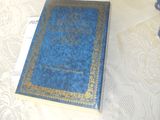 un livre bleu posé sur une nappe blanche