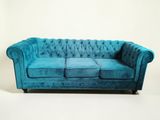 un canapé Chesterfield en velours bleu sur fond blanc