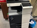 a printer that is sitting on the floor next to a trash can