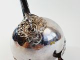 a silver vase with a handle on a white surface