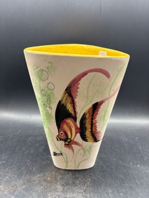 un vase jaune orné d'un poisson, posé sur une table
