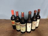 six bottles of wine are lined up on a wooden table