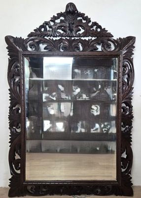 un miroir décoré, avec une étagère remplie de livres, devant un mur blanc