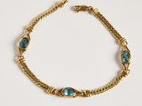 Gros plan sur un bracelet en or orné de pierres bleues