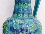a blue and green vase sitting on a white surface