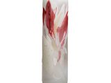 une bougie ornée d'une fleur rouge et blanche, posée sur une surface blanche
