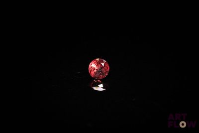 une image représentant un diamant rouge posé sur une surface noire