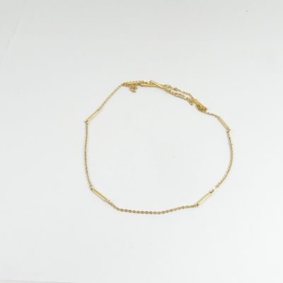 un bracelet en chaîne dorée orné d'une petite perle sur fond blanc