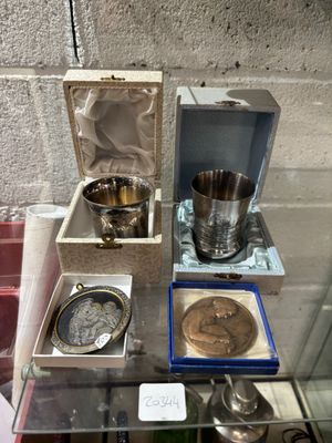 une table en verre sur laquelle sont disposés des objets en argent, dans une vitrine