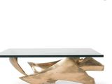 a gold coffee table with a glass top and a metal base