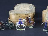 plusieurs figurines représentant des personnes à cheval ou dans des calèches devant une boîte