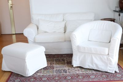 two white chairs and a ottoman in a living room