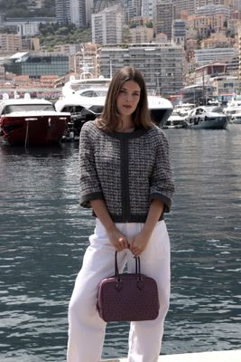 une femme debout sur un quai, un sac à main à la main