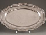 une assiette en argent posée sur un socle transparent, sur une table