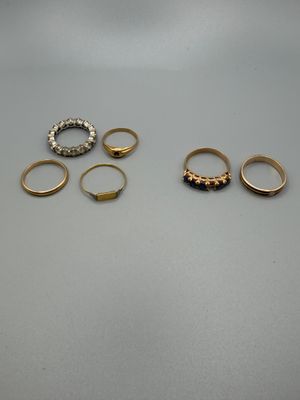 trois bagues en or et deux bagues en argent posées sur une table