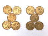 several gold coins are arranged in a row on a white surface