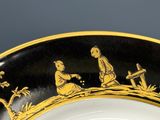 une assiette noire et dorée sur laquelle figure l'image d'un homme et d'une femme