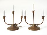 une paire de chandeliers anciens en laiton avec des bougies blanches