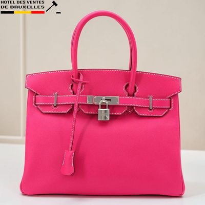 un sac à main rose muni d'un cadenas, posé sur une table