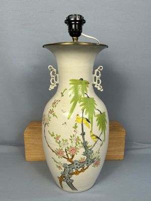 a white vase with a bird on it on a wooden stand