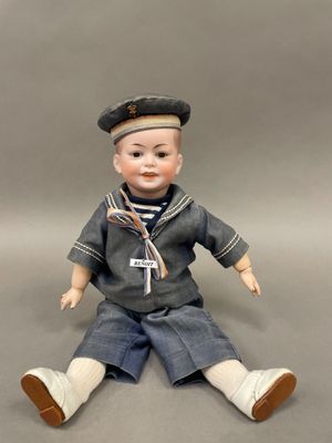 une poupée assise par terre, vêtue d'un costume de marin