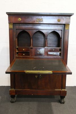 un vieux bureau en bois avec un plateau noir et des détails dorés