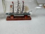 a small model ship in a glass bottle on a wooden stand