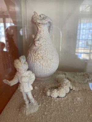 une petite figurine dans une vitrine, à côté de laquelle se tient un petit garçon