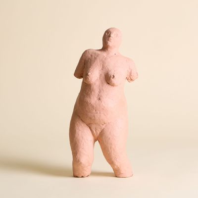 une sculpture rose représentant une femme debout sur une surface blanche