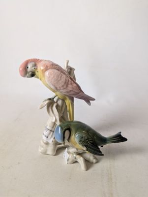 two figurines of parrots sitting on a tree branch