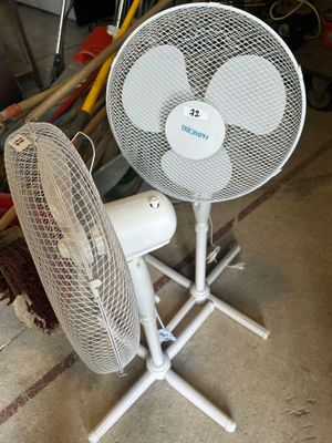 un ventilateur blanc posé sur un support dans un garage
