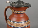 a brown pitcher with a black lid on a gray surface