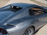 the rear end of a silver sports car parked on the side of the road