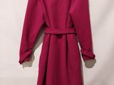 a red coat is hanging on a hanger on a white wall
